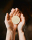 lotion bar out of tin held in hands
